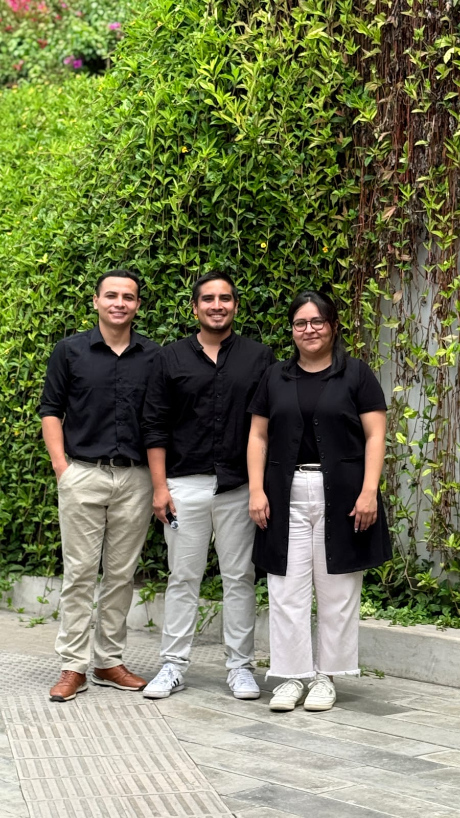 Tres integrantes del equipo de R'HOME de pie frente a un jardín vertical
