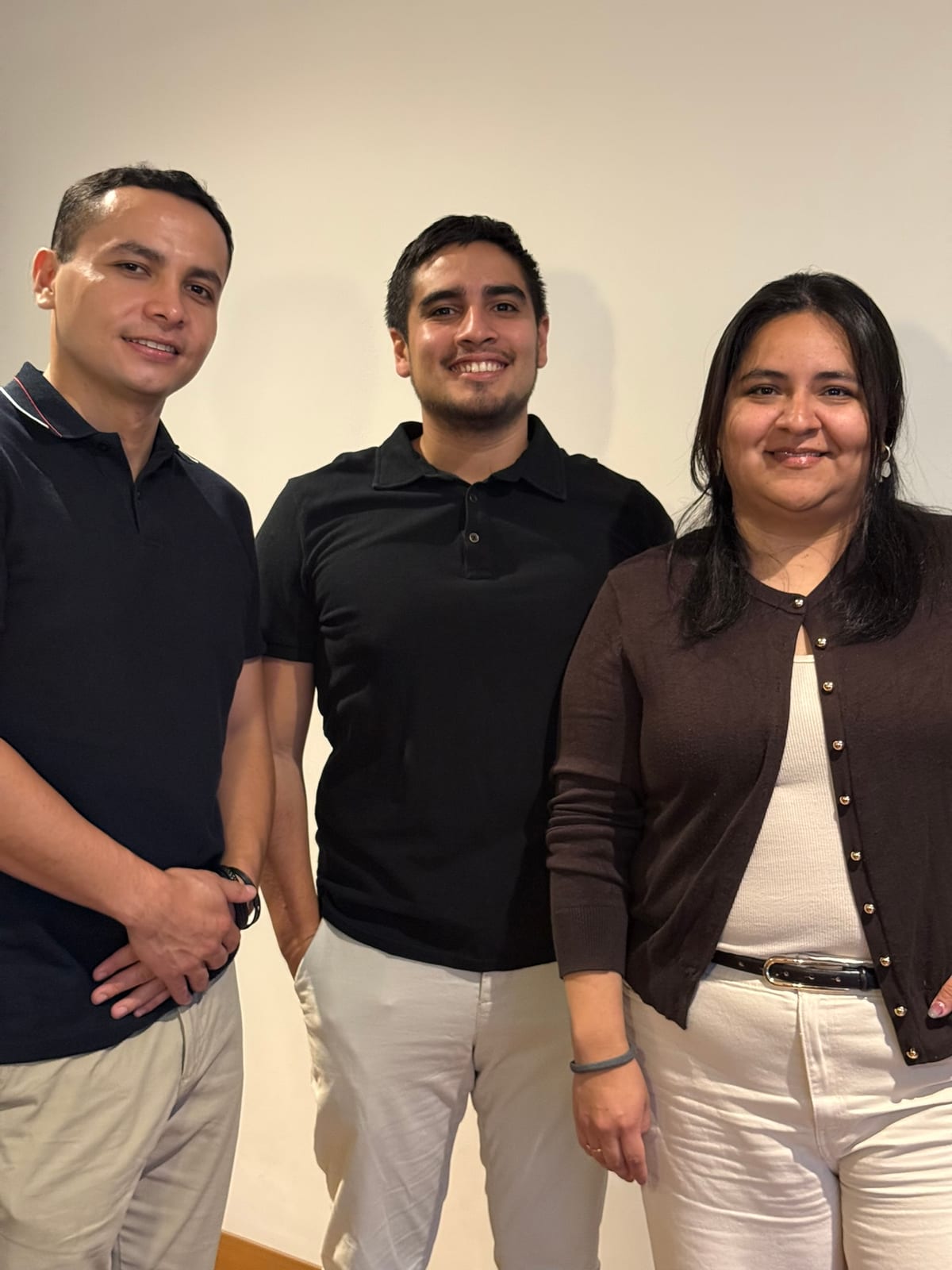 Tres integrantes del equipo de R'HOME posando juntos frente a una pared blanca